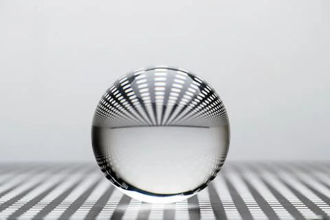 Low angle close up image of a glass toy sphere on a square holed black lattic Stock Photos