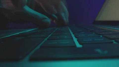 Low angle close up of male hands typing on laptop keyboard with cyan and pu.. Stock Footage 337543101