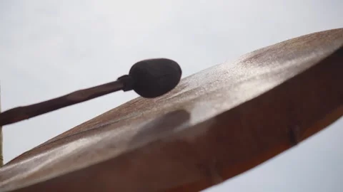 Low-angle close-up of a musician striking a traditional frame drum with a Stock Footage 343381552