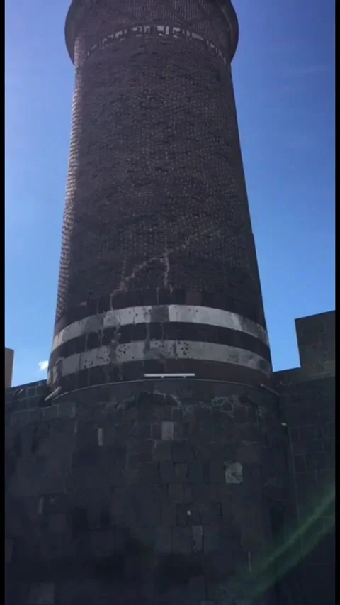 A low-angle, close-up shot of the base and shaft of a tall, historic brick Stock-Footage 333376721