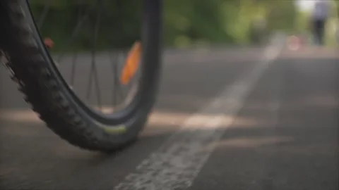 Low angle close up shot of a bycicle sport bike tire wheel moving slowly on ceme Stock Footage 132672370