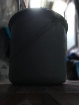 This is a low-angle, close-up shot of a gray bucket sitting on a table, likel Stock Photos