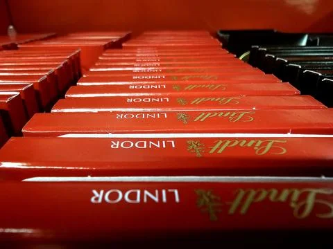A low-angle, close-up shot of multiple red Lindor chocolate bar boxes stacked in Stock Photos
