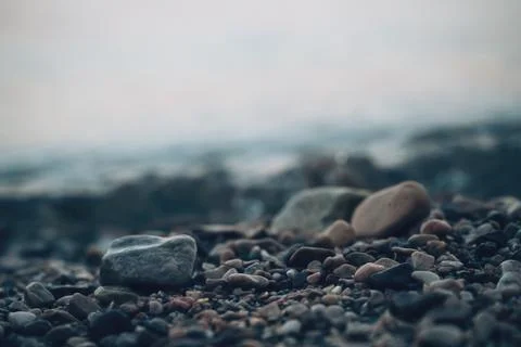 A low-angle close-up shot of small beach pebbles along the shore, with gent.. Fotos Stock