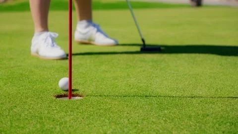 Low angle close up shows golfers legs golfer putts on  white sneakers and ball 库存影片 329413323
