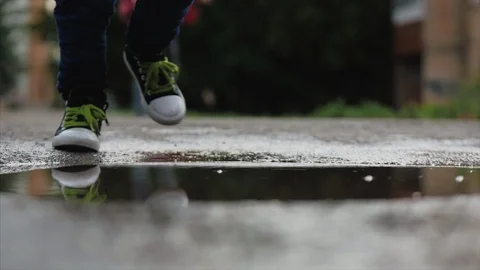 Low angle, close-up, unrecognizable kids running through puddles summer day Stock Footage 112672996
