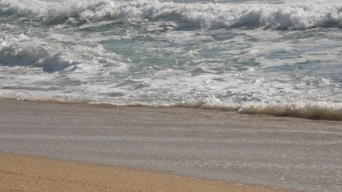 Low angle close up of white foamy waves crashing on a sandy beach Vídeos de archivo 103644571