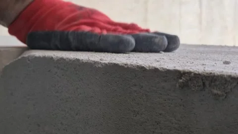 Low angle close-up of worker using hand rasp to sand porous concrete block Vidéo 333588524