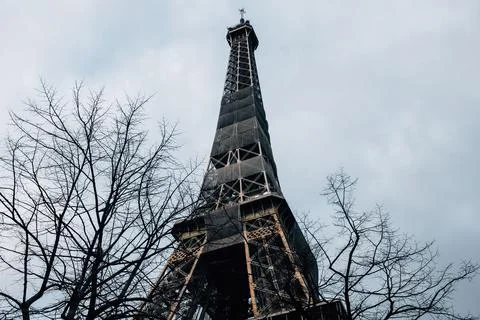 Low-angle closeup of the famous Eiffel tower surrounded by trees in Paris , Fran Stock Photos