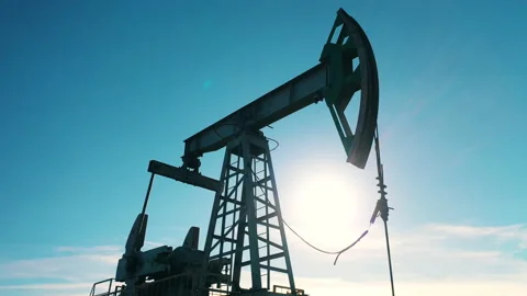 Low-angle closeup of oil pump jack moving against blue sky Stock Footage 145031627