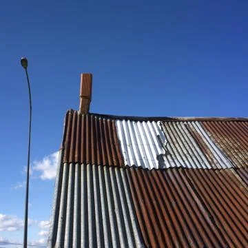 A low angle closeup shot of an old roof with a chimney with a street lamp nex Stock Photos