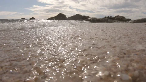 Low angle closeup waves on beach washing over sand and camera Stock Footage 132935532