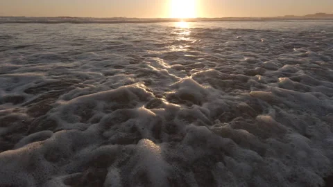 Low angle closeup of waves rushing over sand on beach at sunset. Stock Footage 135419288