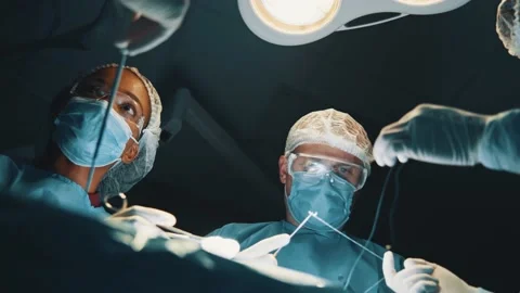 Low angle of the concentrated surgeon man with his assistants sutures stomach Stock Footage 144852510