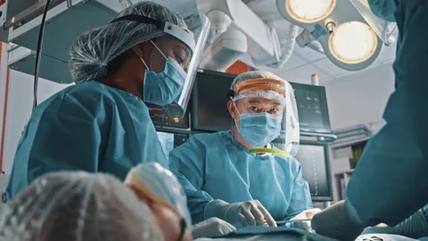 Low angle of the concentrated surgeon man with his assistants sutures stomach Stock Footage 144852884
