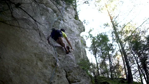 Low angle of cross legged move of rock climber reaching for climbing pocket 動画素材 131837208