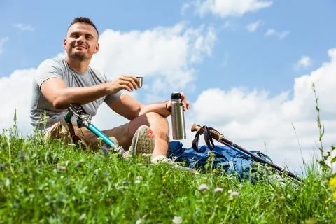 Low angle of a delighted man with prosthesis sitting on the grass Stock Photos