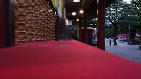 Low-angle dolly shot moving along a red felt rail inside a Japanese Temple Stock Footage 337195625