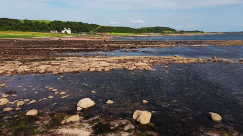 Low Angle Drone Flight Over Rocky Beach with Calm Sea and local Road Stock Footage 342294205
