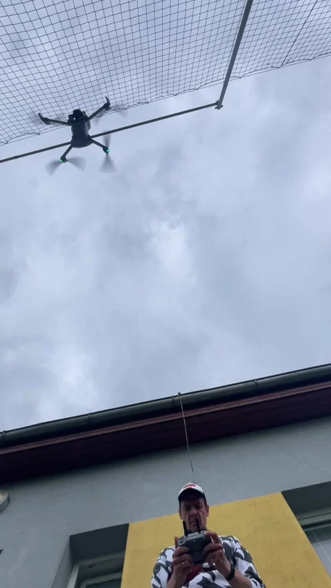 Low-angle drone hovering above pilot beside building under overcast sky view 動画素材 344584739
