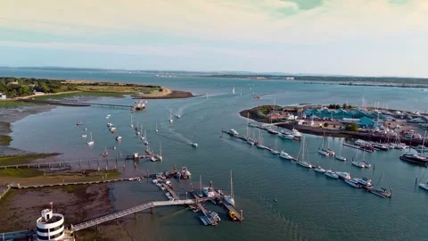 Low angle drone panning right towards Hamble Marina over river mouth at sunset Stock Footage 314596204