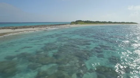Low angle drone past blue water sand beach, dinghy on shore, birds, 4k Stockbeeldmateriaal 124879273