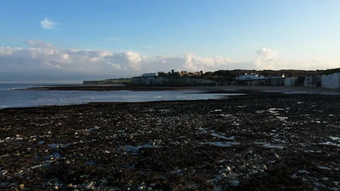 Low angle drone shot flying over rocks at low tide towards castle on cliff top. Stock Footage 146739872