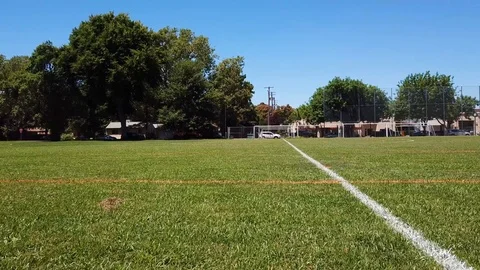 Low angle drone shot following the lines of an empty outdoor soccer field Stock Footage 92753401