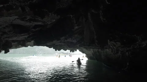 Low angle drone shot following kayakers inside a cave at Halong Bay Видео 288567476