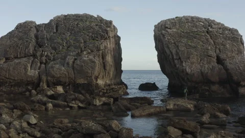 Low angle drone shot going through cliffs with a fisherman during sunrise 4k Stock Footage 137708439
