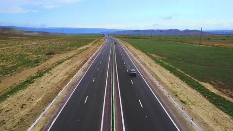 Low-angle drone shot of a highway cutting through vast open countryside Stock Footage 304470205