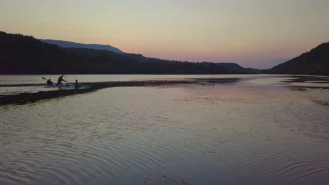 Low Angle Drone Shot Three Men Canoeing  Sunset Lake Stock Footage 159534407
