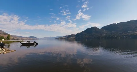 Low angle drone of still lake with boat - early morning Video stock 93480361