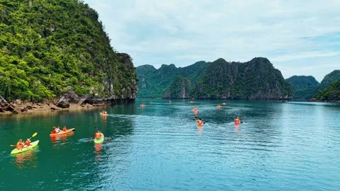 Low angle drone tracking of tourists paddleboarding near towering cliffs 4K Stock Footage 340012030