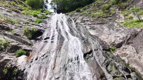 Low-angle drone view of a mountain waterfall flowing down steep rocks Stock Footage 340360391