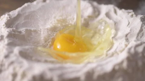 Low angle of egg falling into well of flour in slow motion shot at 120 fps Stock Footage 171484786