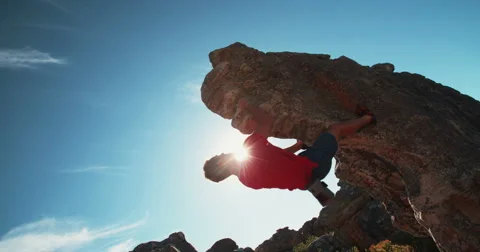 Low angle of extreme free climbing man hanging on rock Stock Footage