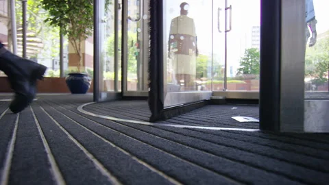 Low angle of feet passing through revolving doors of a building Stock-Footage 243027996