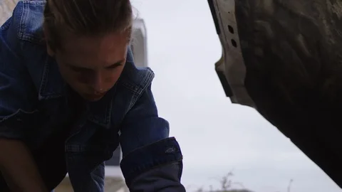 Low angle of a female checking under a bonnet for routine checks on a Video stock 102464057
