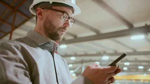 Low Angle of Focused Engineer Using Mobile Phone in Industrial Plant Stock Footage 296265027
