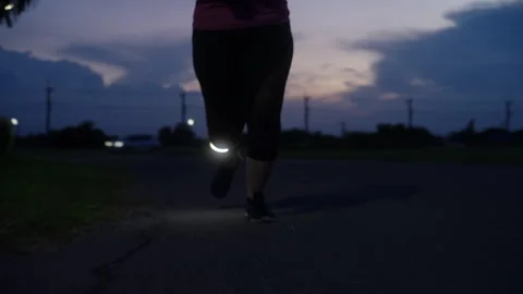 Low-angle front view of a middle-aged Asian woman jogging at twilight Stock Footage 335759671
