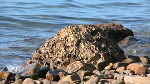 Low angle gently waves hitting rocky shore on bright sunny day Stock-Footage 138266426
