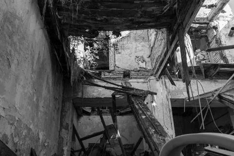 Low angle grayscale shot of abandoned and demolished building from inside. Stock Photos