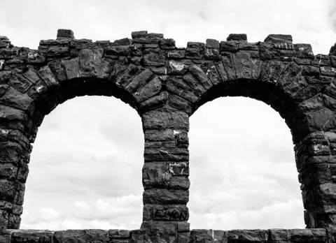 A low angle greyscale shot of the arch-shaped columns made of stone under the 스톡 사진