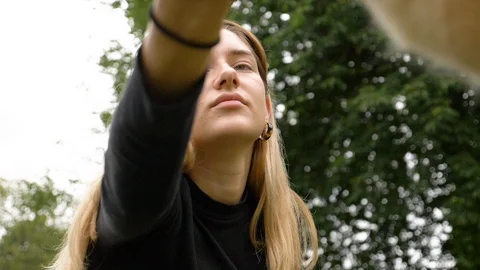 Low angle handheld shot of beautiful young woman stroking dog in park Vídeo Stock 114874050