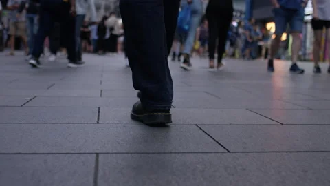 Low angle handheld shot of feet walking through city crowds, in slow motion Stock-Footage 202617280