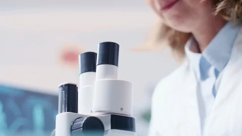 Low angle handheld shot of mature female researcher looking through a microscope Stock Footage 111015465