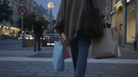 Low-angle handheld shot of a young woman walking with colorful shopping bags in Video stock 117239493