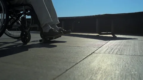 Low angle of a helpful man pushing a wheelchaired person Stock Footage 78089789