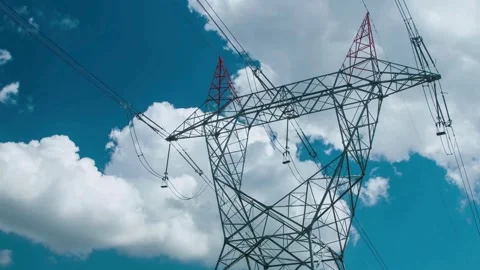 Low angle of high voltage power lines against a blue sky with clouds Stock Footage 332873967